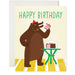 A cheerful birthday card showcasing a bear wearing a party hat, holding a slice of cake in one hand with a cake display on a table. The text says 'Happy Birthday.' From the Karen Schipper Card Collection.