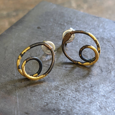 Steel & Gold Coil Earrings featuring a continuous blackened steel coil accented with 23k gold, shown from the front.