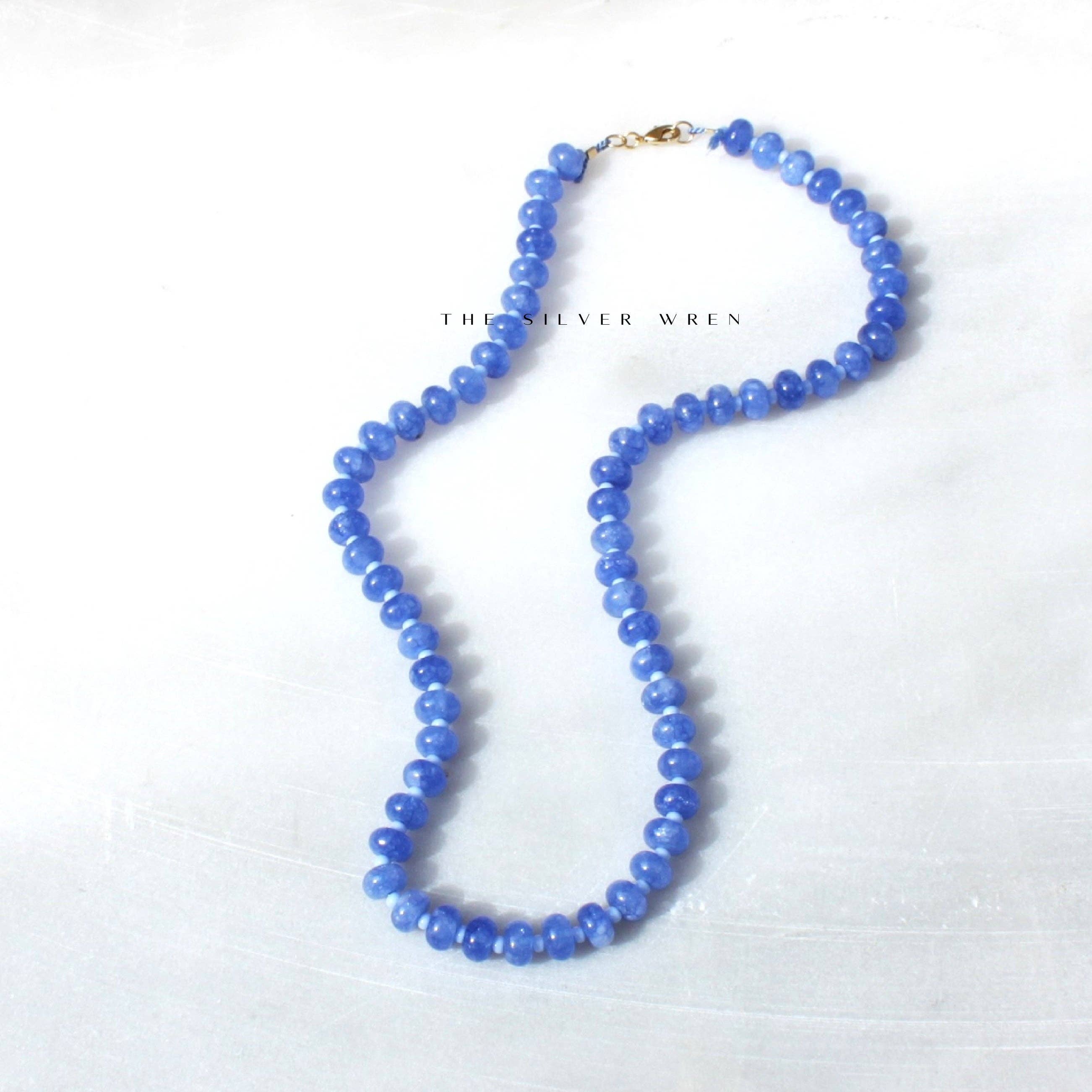 Flat lay view of the Cornflower Stone Candy Beaded Necklace by The Silver Wren, featuring lustrous blue jade beads on a light surface.