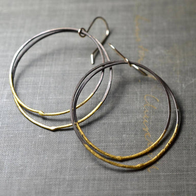 Steel & Gold Double Hoops earrings by Metamorphosis Metals, featuring hammered darkened steel circles, 23k yellow gold leaf accents, and 14k gold-filled earwires—industrial edge with a little golden flair.