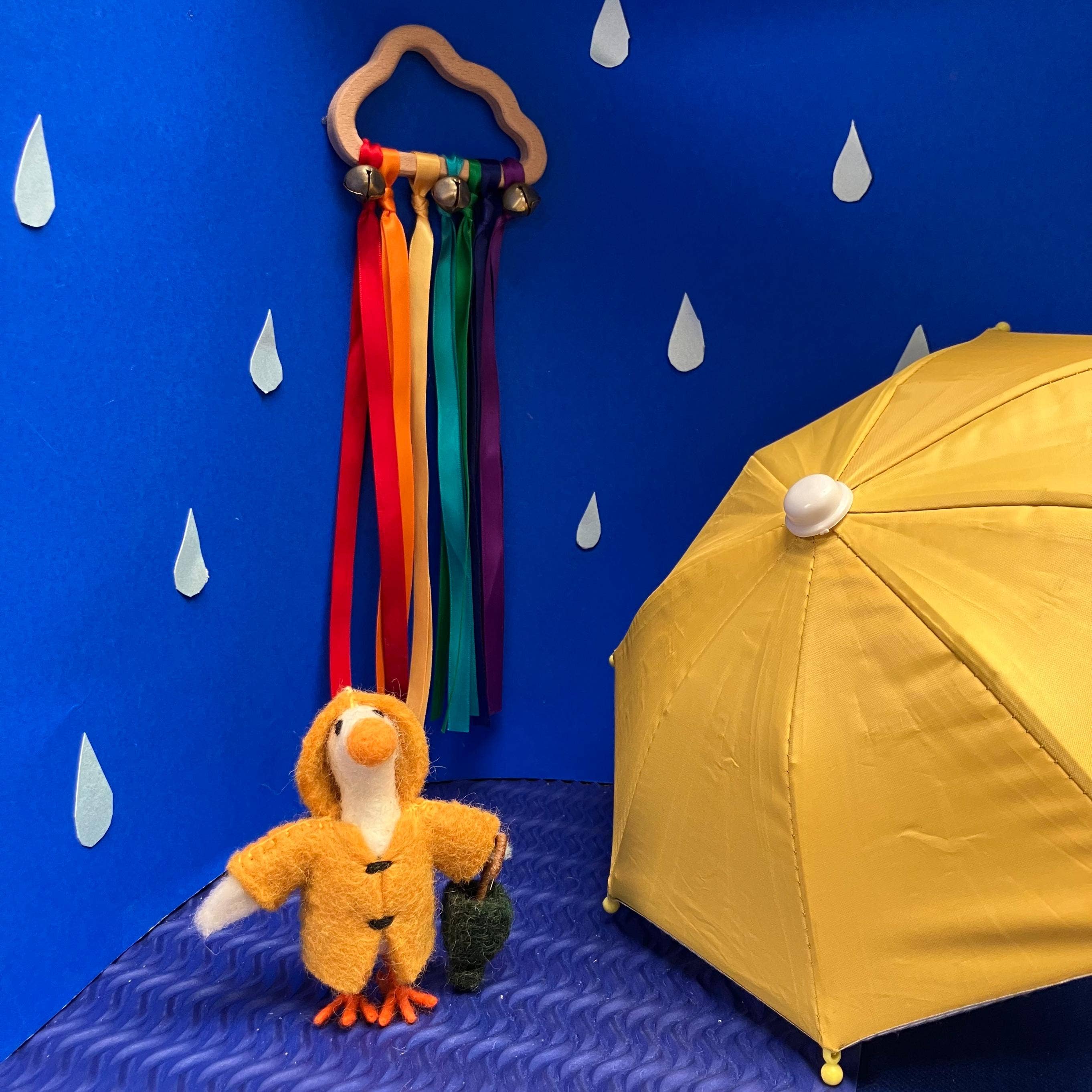 Felted goose ornament in yellow raincoat holding a green umbrella