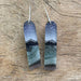 Fernworks Crystal Hills Earrings featuring hand-painted landscapes under a night sky, made with polished resin and adorned with amethyst and jasper accents. Each earring measures approximately 1.5" x 0.5".