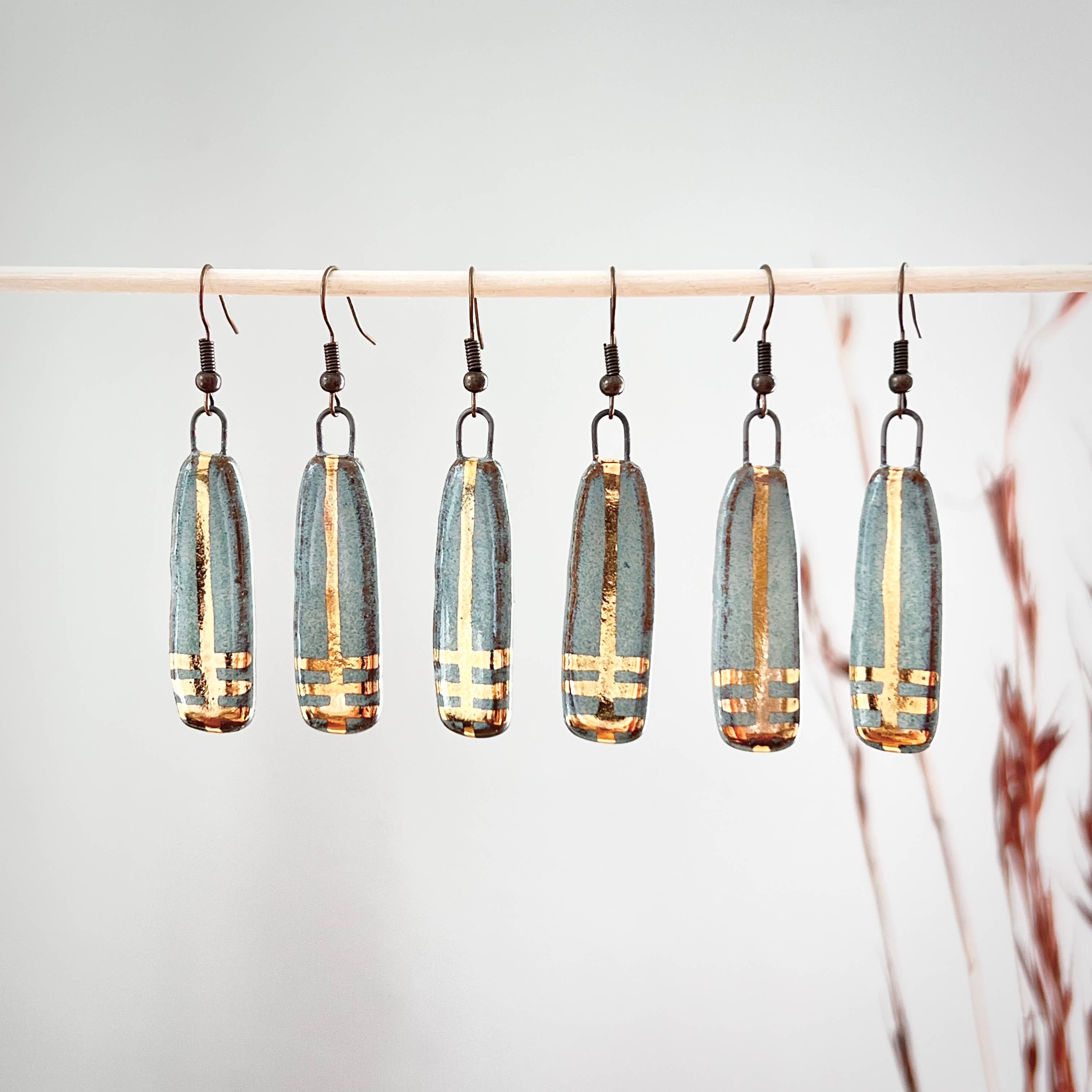 Turquoise Long Line Designed Earrings from The Artifact House, arranged in a row to display the variety of handmade pieces, each with gold accents.