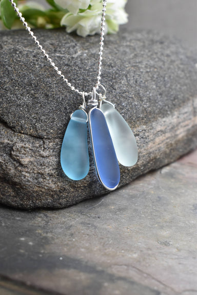Eco glass triple charm Necklace showcasing sea glass jewelry with three ocean-inspired charms in blue and aqua colors, perfect for coastal chic aesthetics.