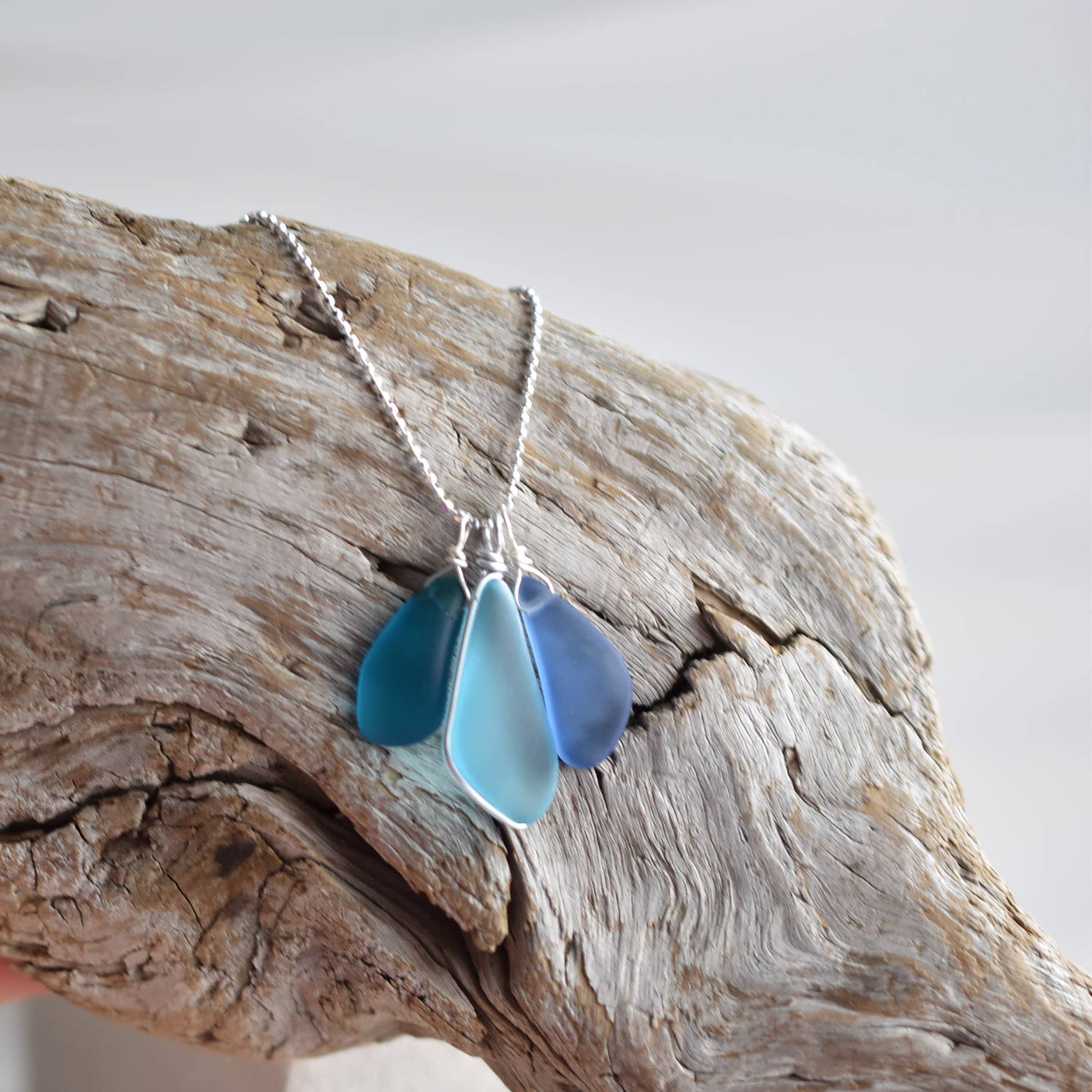 Elegant view of the Blue Eco Glass Trio Sterling Silver Necklace by Whitelotus Design, featuring three stunning blue glass drops on a sterling silver chain.