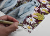Emily Uchytil hand-signing the meerkats fine art print, capturing the artist's personal touch on the floral-themed artwork.