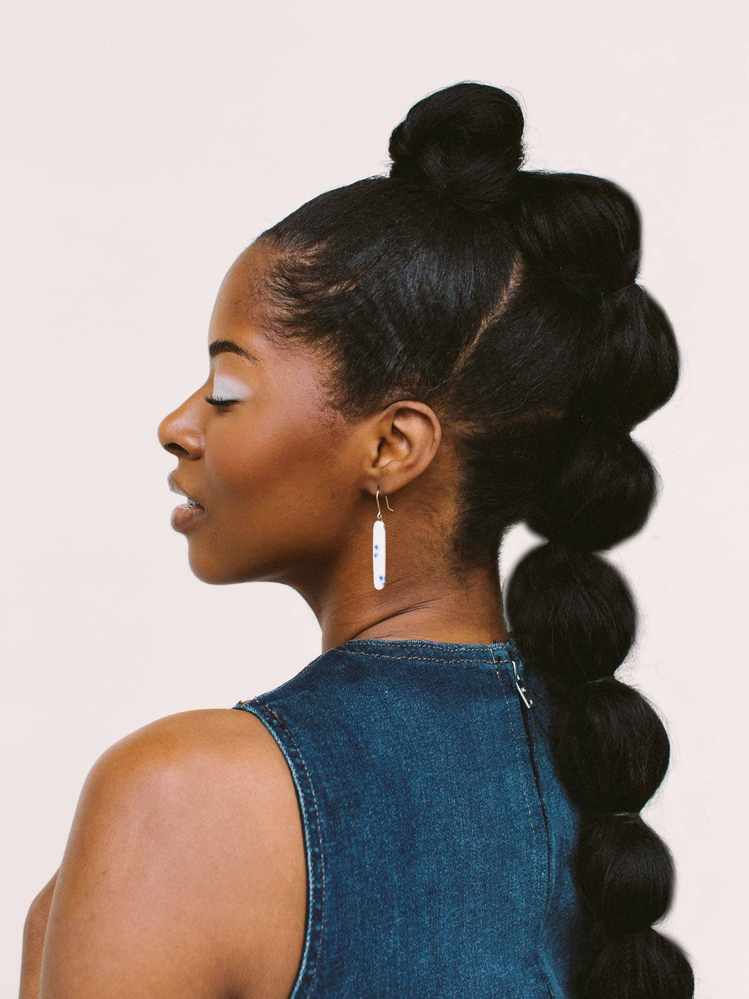 Close-up profile shot of a woman adorned with Skinny Dip Earrings by Twenty Two West, highlighting her stylish look and elegant ear embellishments.