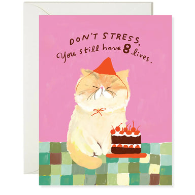 A whimsical greeting card featuring an illustration of a cat with a party hat, accompanied by a birthday cake. The card reads 'Don't Stress, You Still Have 8 Lives.' Part of the Karen Schipper Card Collection.