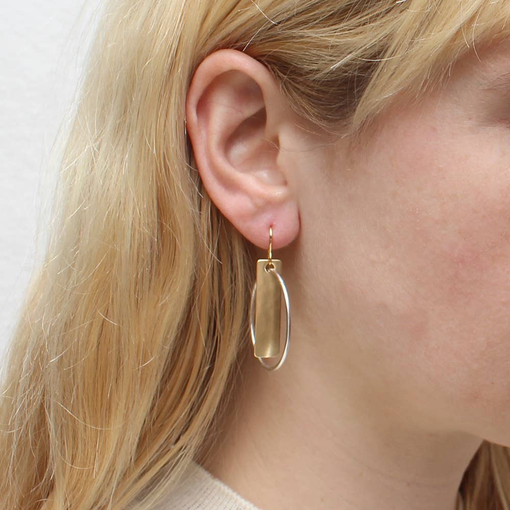 Close-up of Rectangle with Interlocking Ring Earring featuring a lightly hammered brass finish and interlocking silver ring, designed by Marjorie Baer.