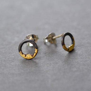 Steel and Gold Tiny Circle Studs by Metamorphosis Metals, featuring blackened steel circles with 23k gold gilded accents and sterling silver posts—tiny earrings with a big personality.