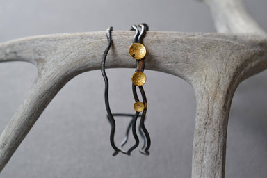 Gold Pool Linear Cuff Bracelet featuring forged steel wire, brazed brass, and concave 23k gold discs in a sleek half-inch-wide design—your wrist’s tiny golden pool.