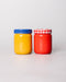 Two jars, one yellow with a blue lid and one red with a red and white checkered lid