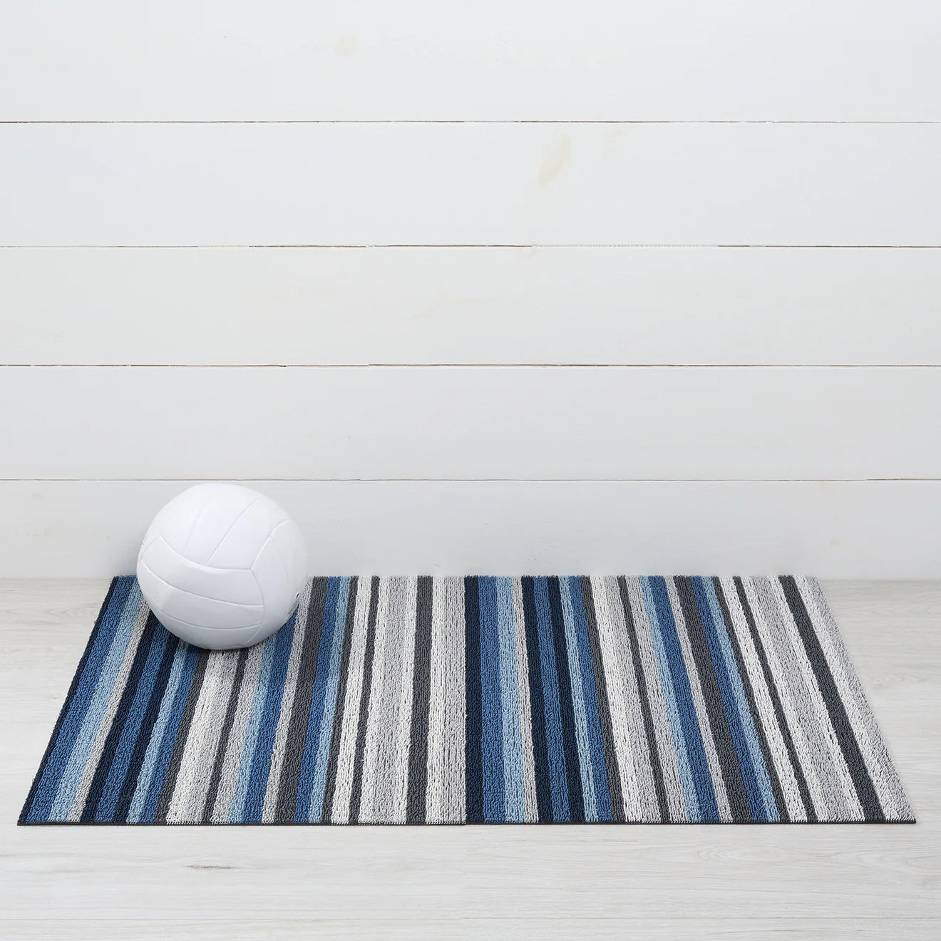 Close-up view of the Horizon Stripe Shag Mat in Deep Sea by Chilewich, highlighting the resilient vinyl backing designed for both indoor and outdoor use.