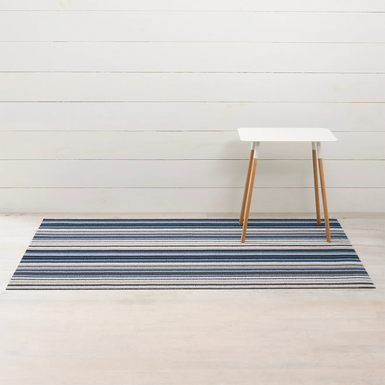 Horizon Stripe Shag Mat in Deep Sea featured in a mudroom, illustrating its dynamic color patterns and durability against mold and mildew.