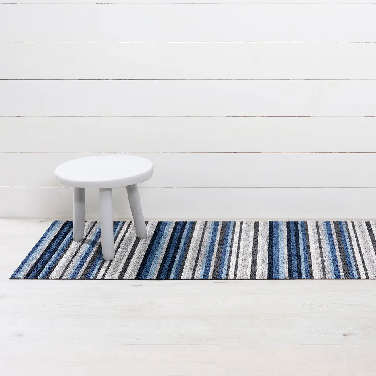 Horizon Stripe Shag Mat in Deep Sea displayed in a bathroom setting, emphasizing its stylish and functional design to keep spaces clean.