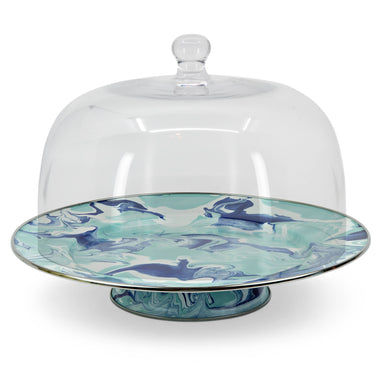 Enamelware Lagoon Cake Plate by Crow Canyon Home featuring a marbled design in cobalt blue and sea glass colors, displayed under a glass dome.