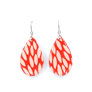 Close-up of Teardrop burst Chiyogami titanium earrings in red, featuring UV-cured resin finish and delicate titanium wire hooks.