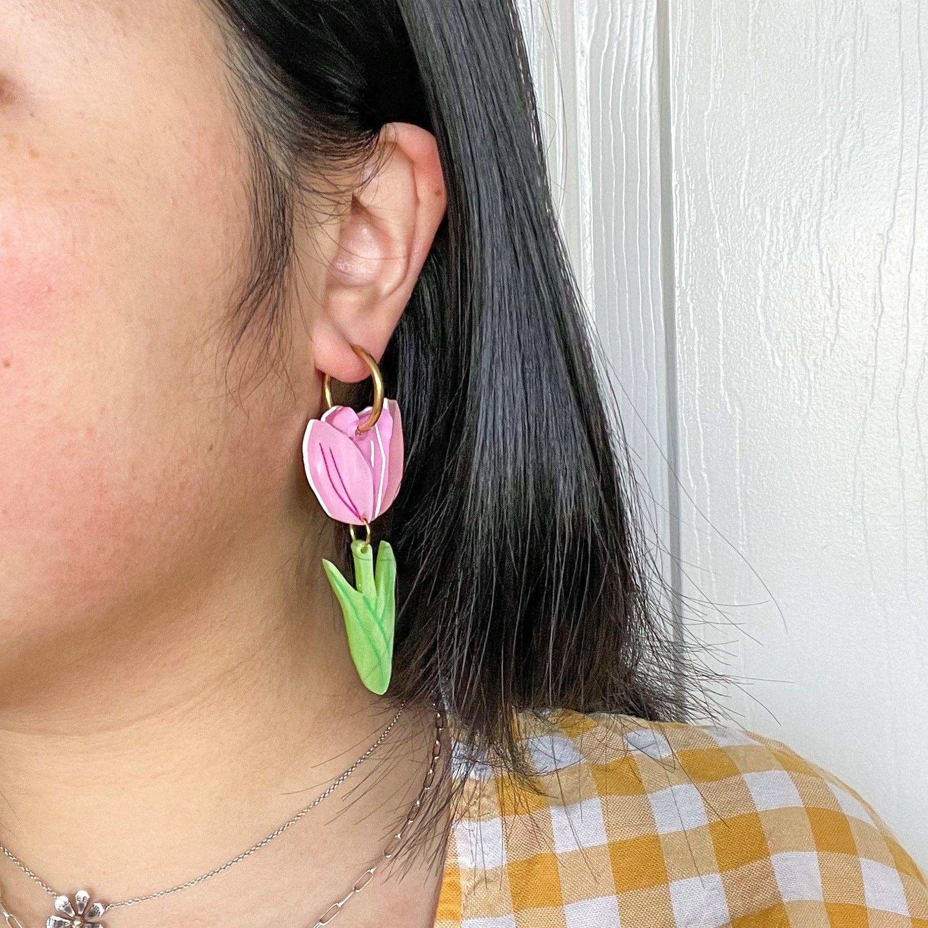A person wearing pink Spring Tulip earrings by Sunnie Creative, highlighting the unique handmade design and vibrant colors against a casual outfit.
