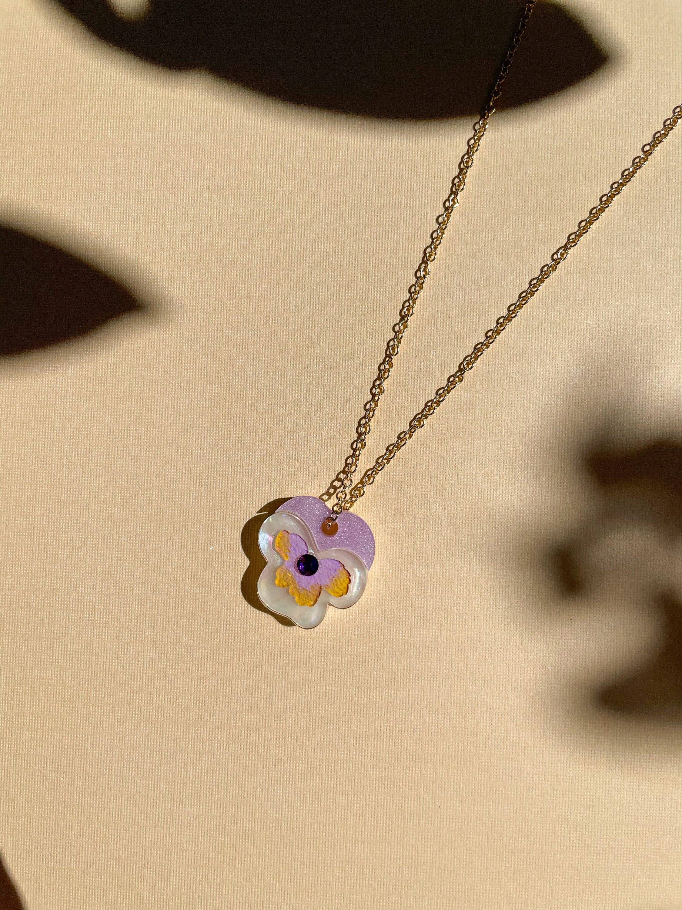 Mini Pansy Necklace by Sunnie Creative showing a delicate purple and white flower pendant, reflecting the charm of handcrafted jewelry.