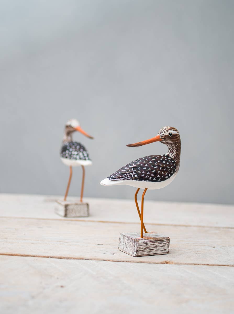 Mini Yellow Legs wooden ornament by Aviologie, showcasing intricate hand-carving and vibrant painting, displayed on a rustic wooden base.
