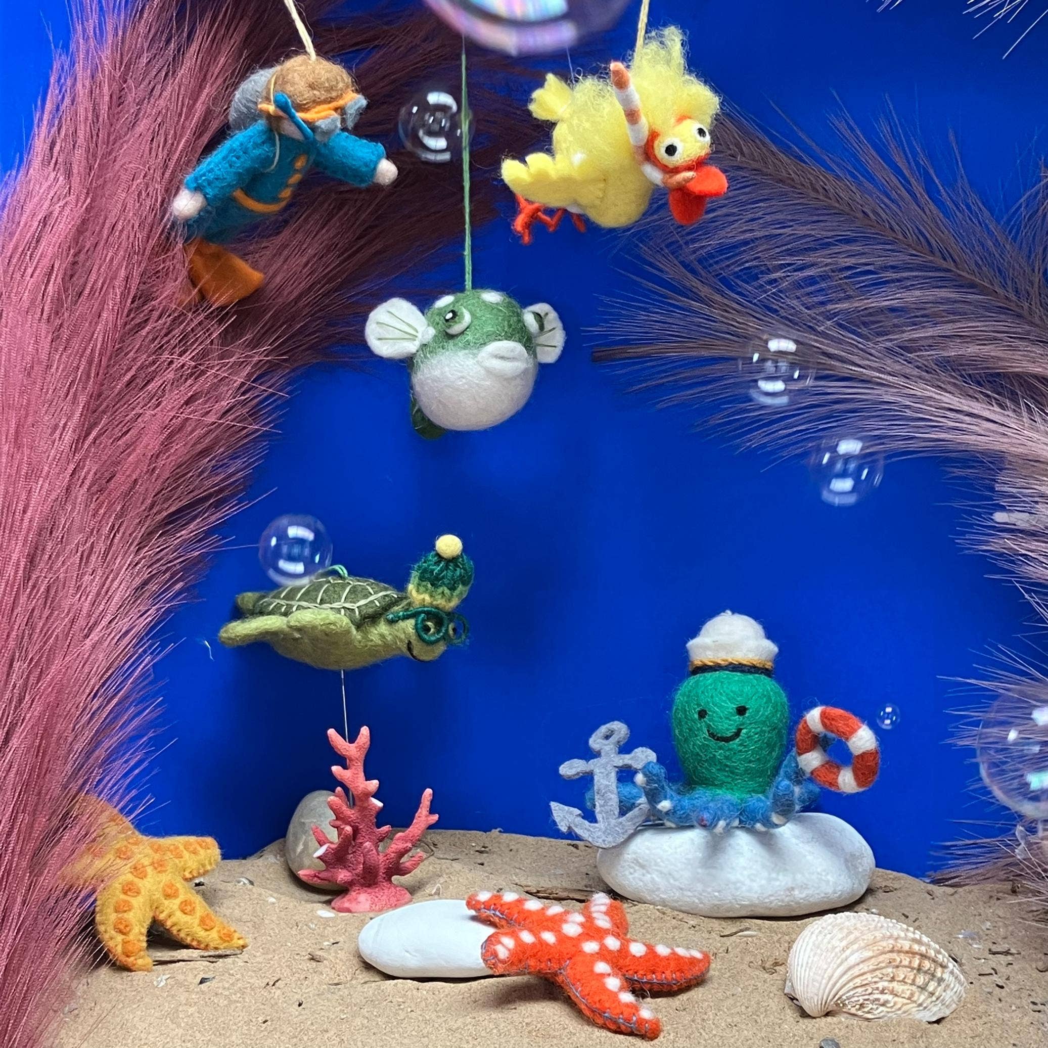 felted ocean-themed ornaments on a blue background with sand and sea elements.