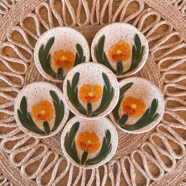 A beautiful arrangement of six Globe Mallow Sgraffito Tea Rests by Tough Kitty Designs, featuring hand-painted orange flowers on a speckled background, perfect for holding small items.