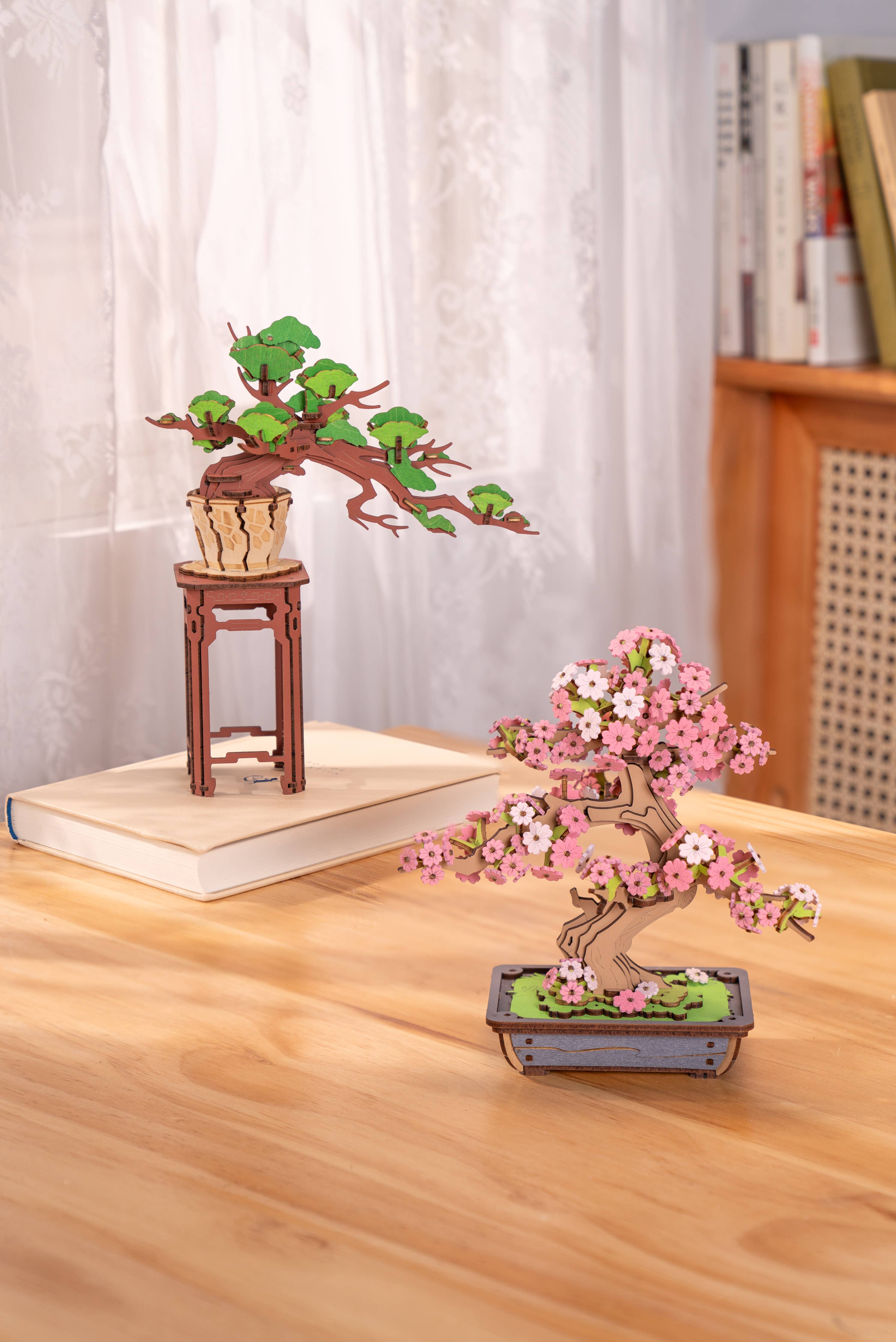 Sakura Bonsai Modern Wooden Puzzle by Hands Craft showcased on a wooden table featuring two completed wooden bonsai trees, illustrating the elegant designs.