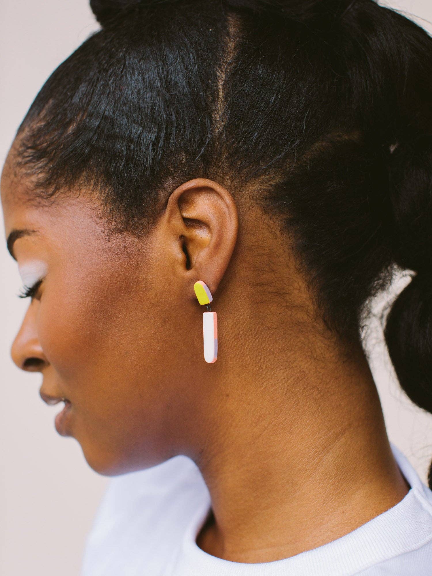 Close-up of Split Dip Earrings by Twenty Two West on a woman's ear, highlighting the unique design and bright colors that add a playful touch to her look.
