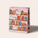 Bookshelf Cats Pink Gift Bag by Seltzer Goods features whimsical illustrations of cats on bookshelves in shades of pink, white, and red, ideal for book lovers and cat enthusiasts.