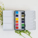 12 Color Mini-Travel Watercolor Paint Palette with compact design, featuring a durable metal tin, and built-in mixing palette for artists on the go.