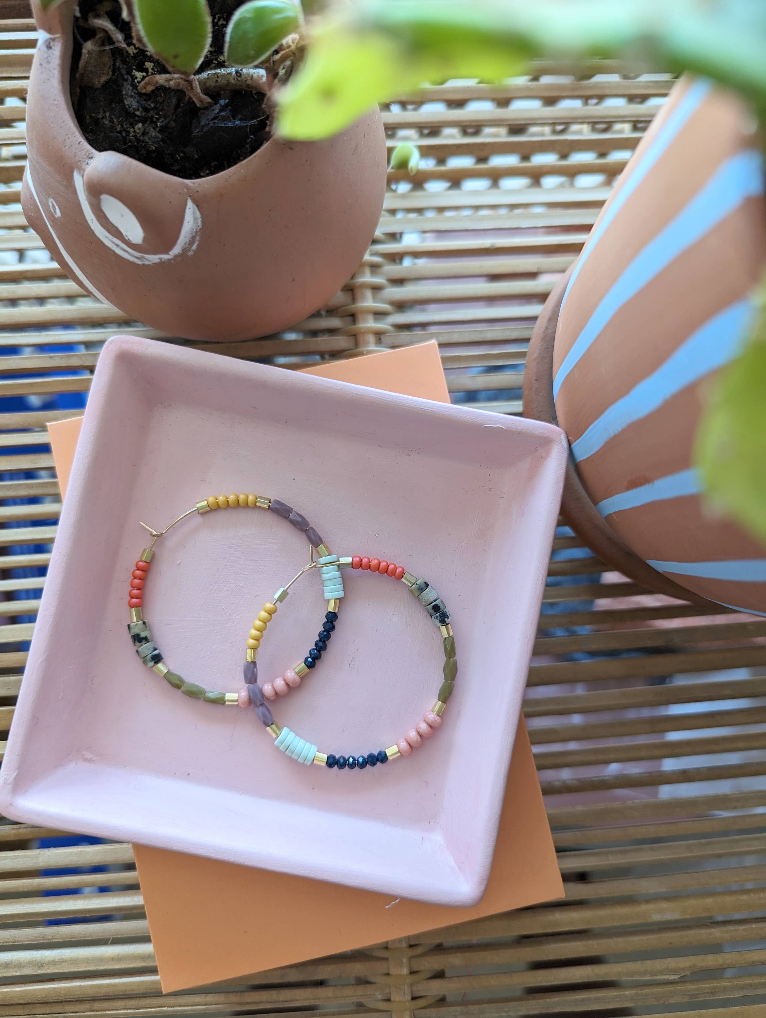 Colorful beaded Gold hoop earrings on a pink tray