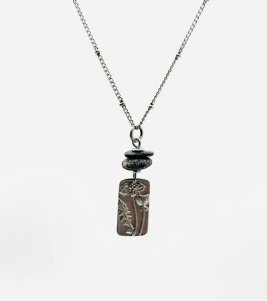 Flower Power Necklace by Suzanna Garrett Designs — a dainty wildflower pendant gets a little extra texture from dark river stone pebbles