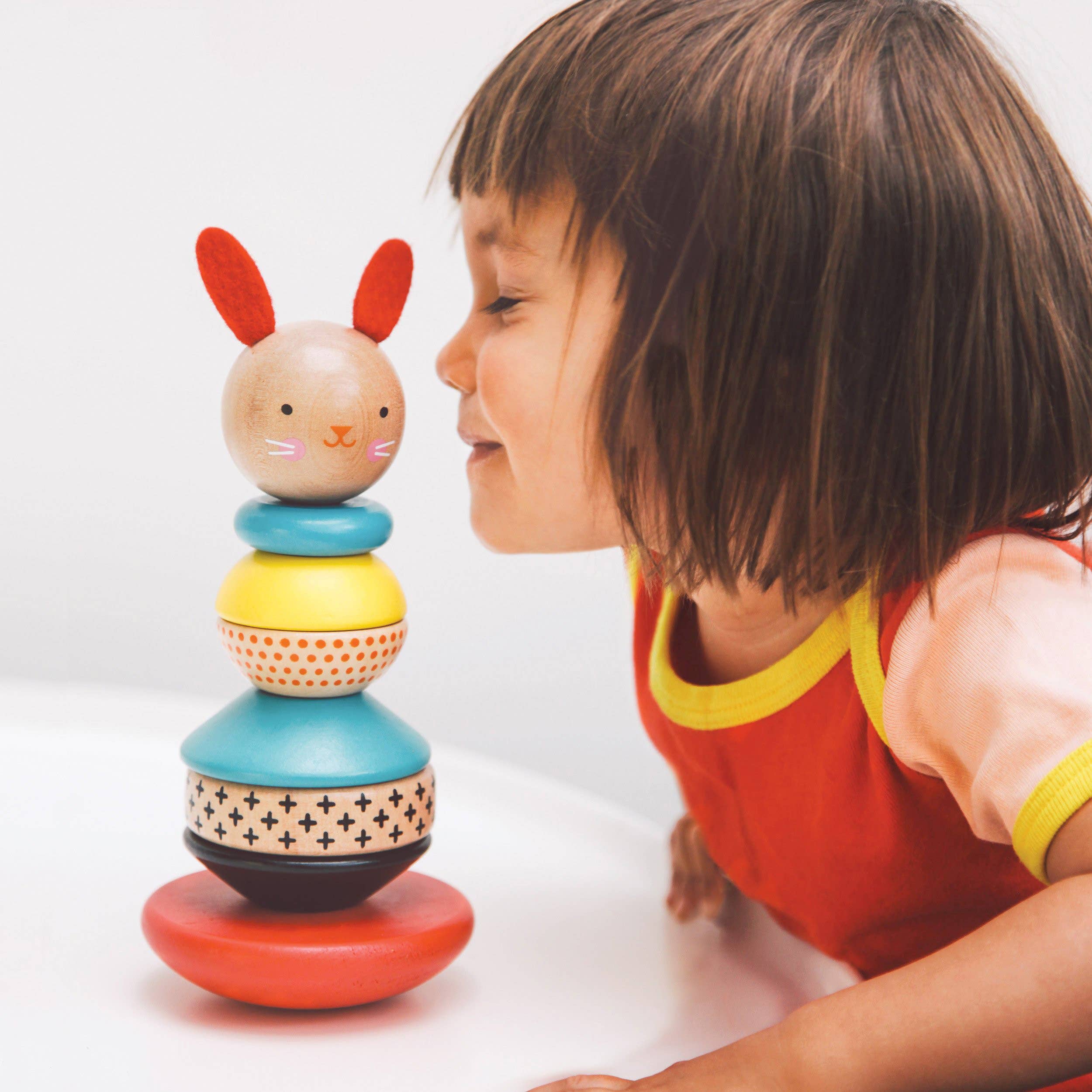 Little girl with Wooden Rabbit Stacker Toy by Petit collage