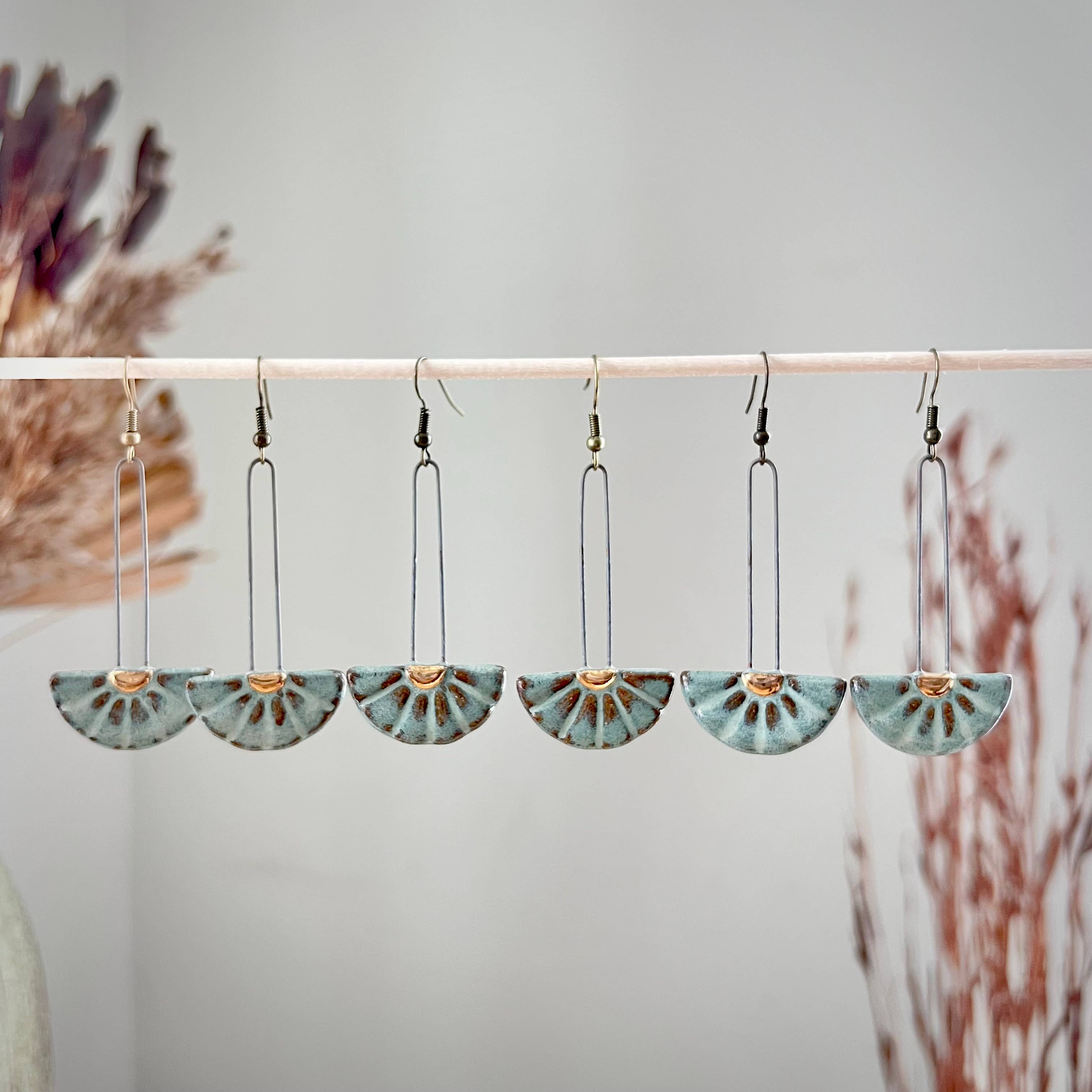 Turquoise Sun Burst Ceramic Earrings by The Artifact House displayed in a creative arrangement, showcasing the unique sun burst design with a smooth, luminous glaze.