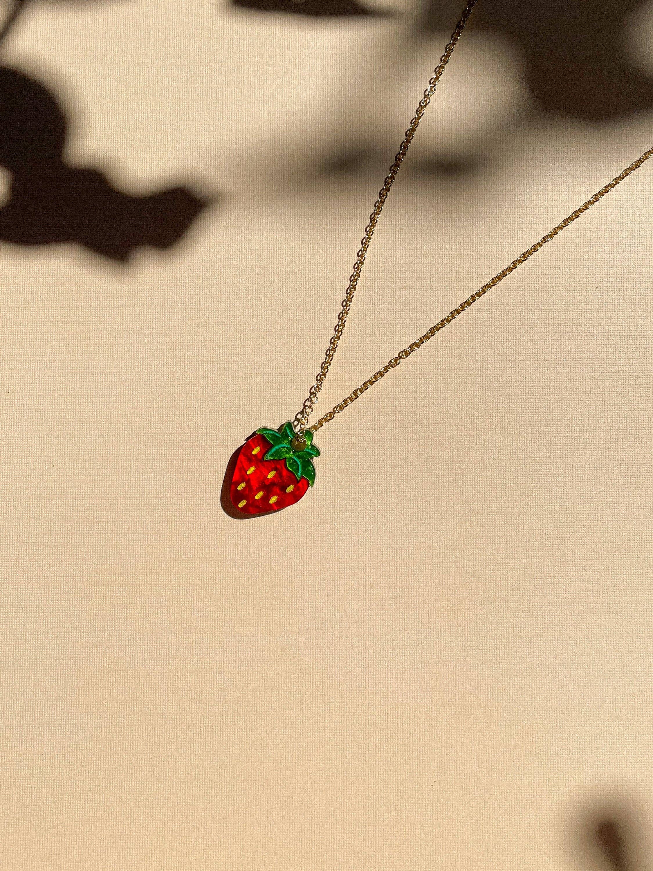 Mini Strawberry Necklace by Sunnie Creative, featuring a vibrant strawberry pendant on a delicate chain against a soft background.