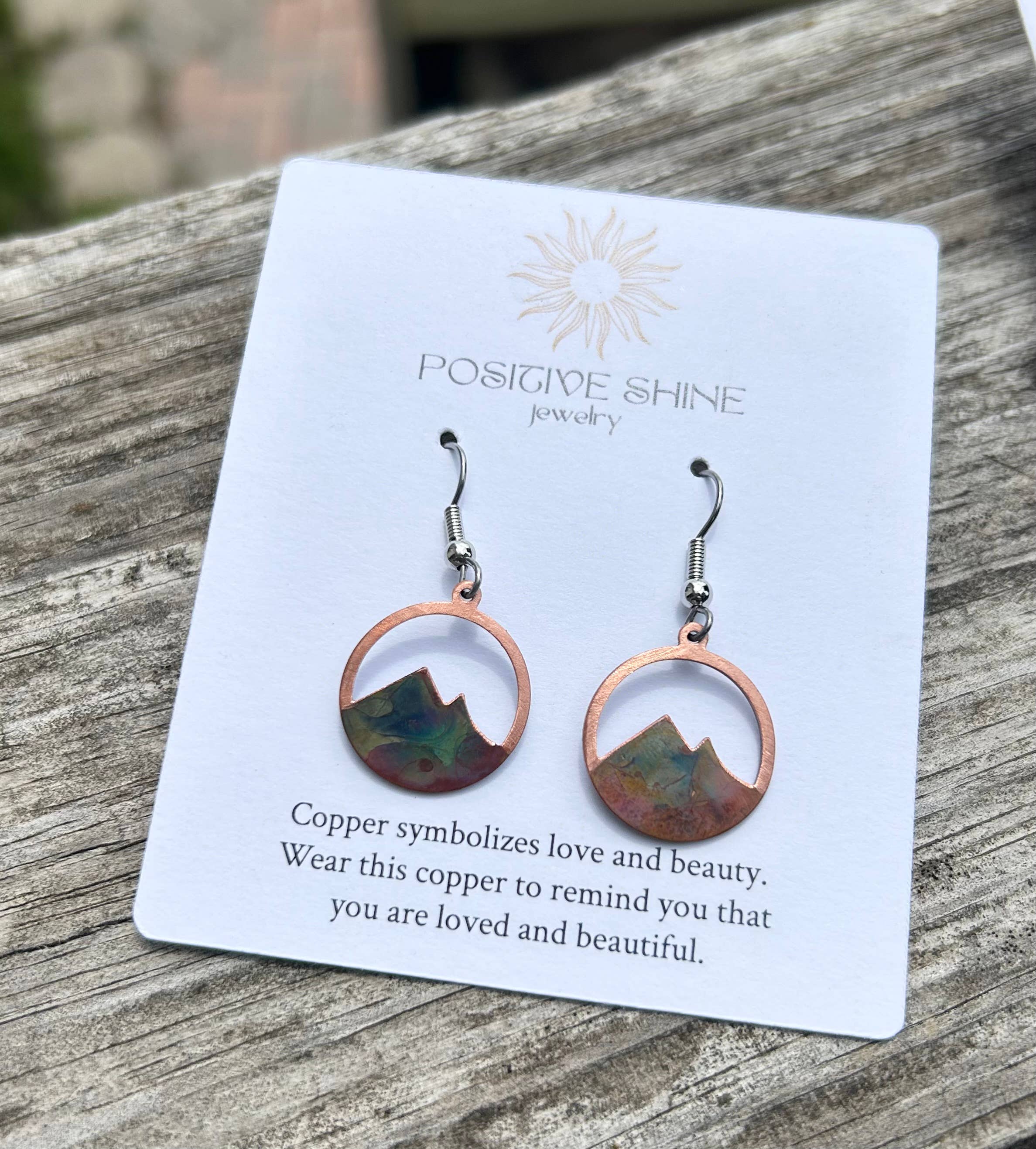 Mountain Earrings featuring colorful brushed copper in a circle design, hanging from stainless steel ear wires.
