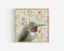 Framed art print of a hummingbird on a floral patterned background.