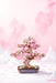 Sakura Bonsai Modern Wooden Puzzle by Hands Craft, presenting an elegant cherry blossom bonsai tree puzzle in pink hues, surrounded by a soft pink backdrop and snow-capped mountains.