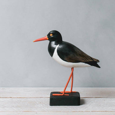 Handcrafted wooden American Oyster Catcher bird by Aviologie, showcasing intricate detailing in black and white with a bright orange beak, standing on a black base.