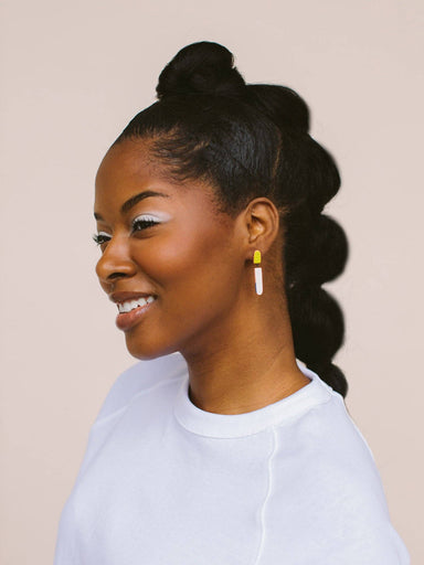 A woman wearing Split Dip Earrings by Twenty Two West, smiling against a neutral background, showcasing the earrings' vibrant colors and elegant design.