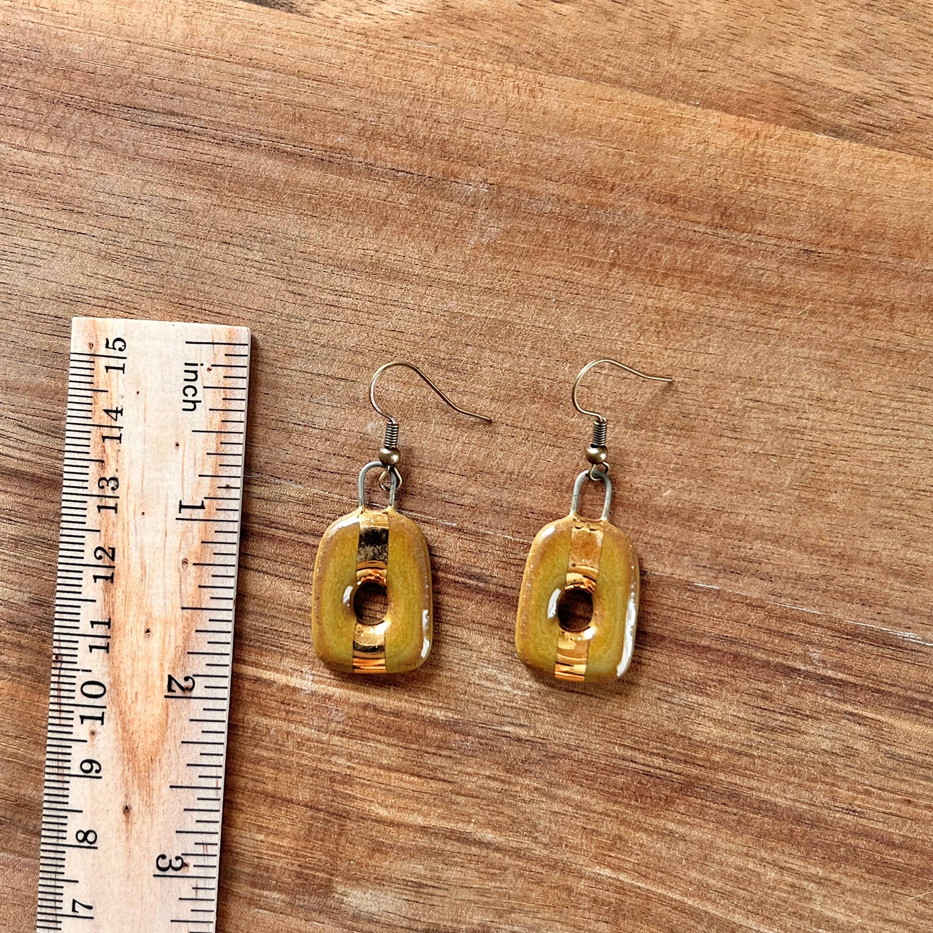 Olive Square Loop Ceramic Stoneware Earrings next to a ruler for size reference, showcasing their unique design and craftsmanship by The Artifact House.