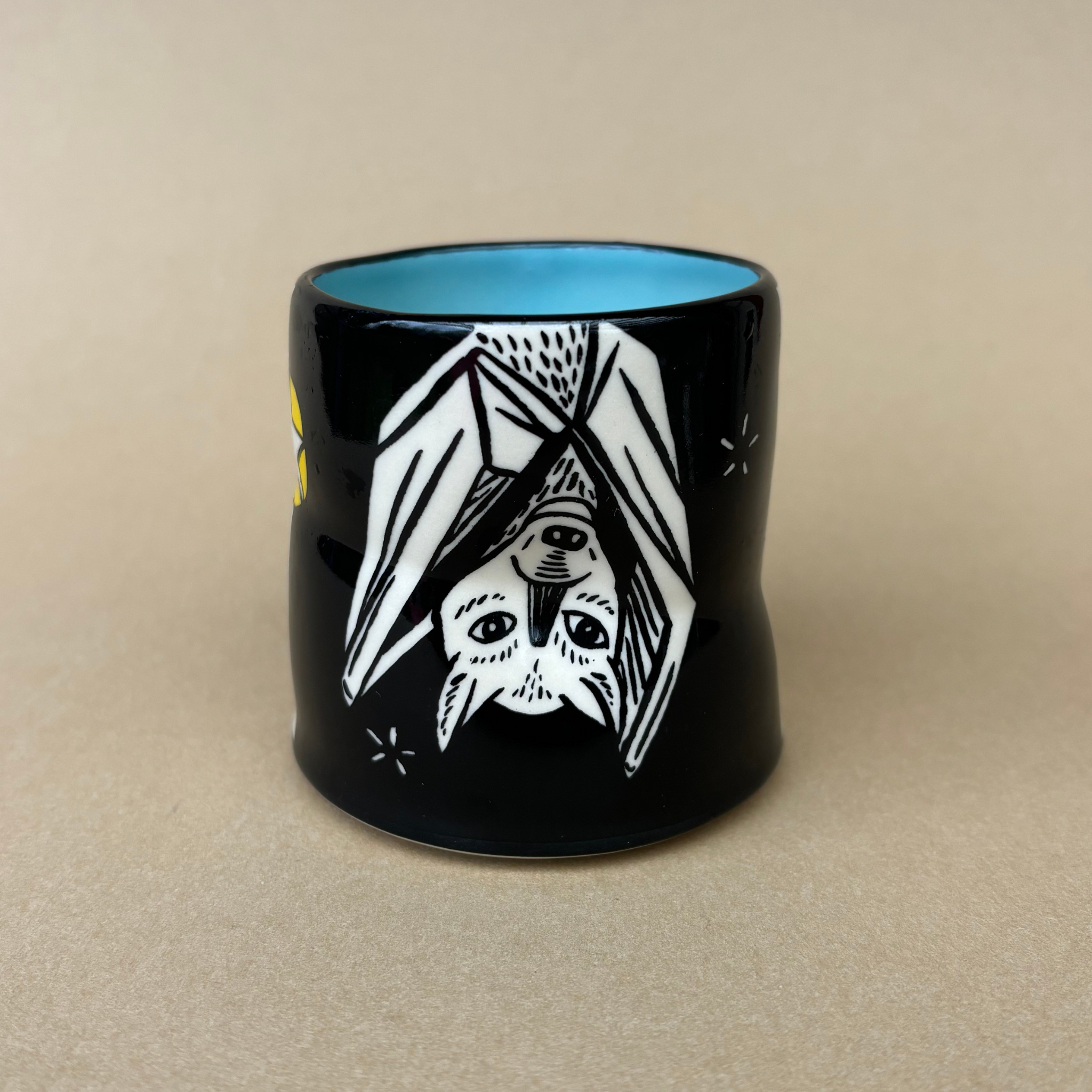 Medium Lucky Bat Cup by The Bowl Maker, featuring an artistic design of a bat in flight with a vibrant blue interior.