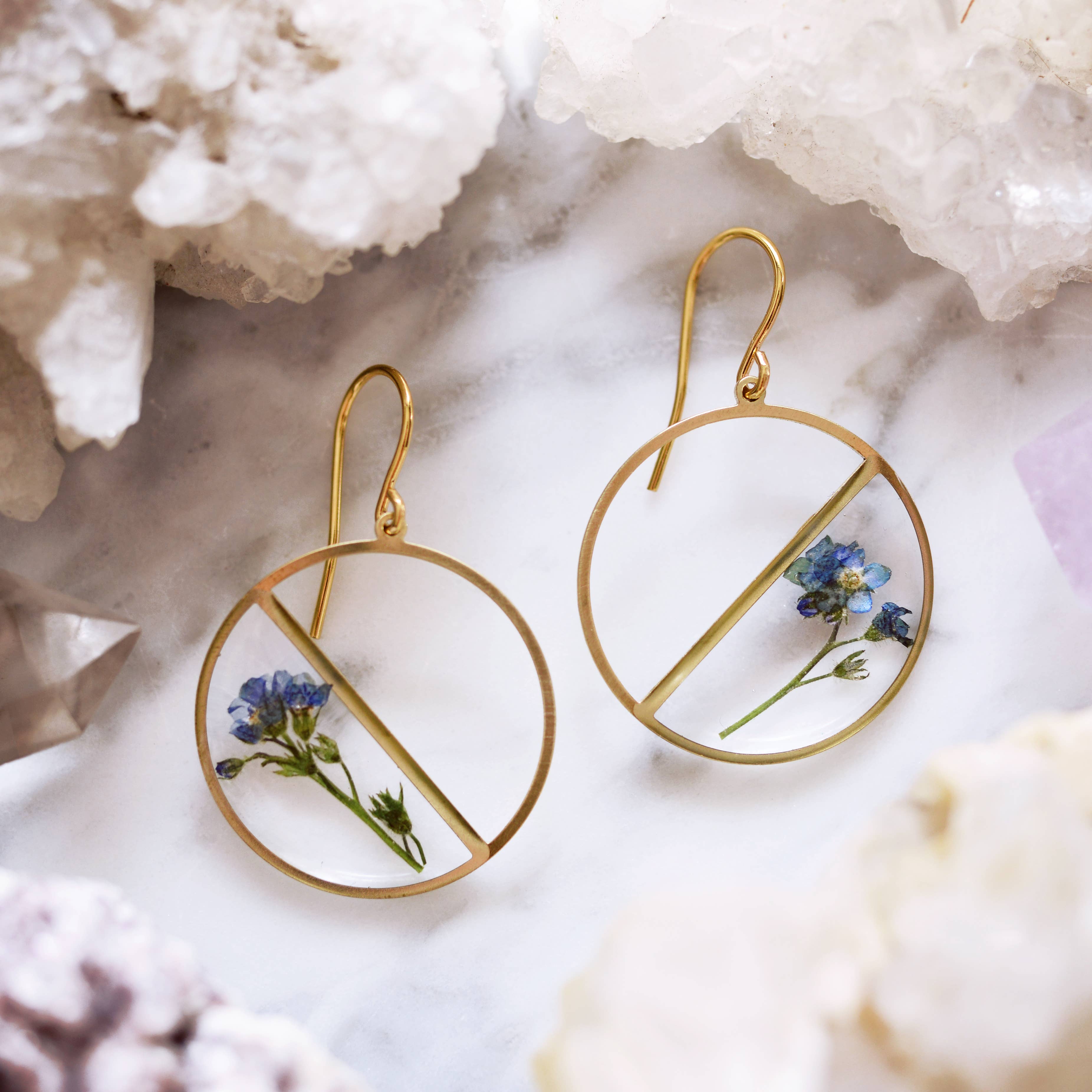 Forget Me Not Pressed Flower Earrings featuring real pressed flowers and resin in a stylish round shape with brass frames and gold plated ear wires.