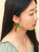 Model showcasing Rainbow Carrot Dangle earrings by Sunnie Creative, featuring vibrant green and colorful carrot designs, perfect for adding a playful touch to any outfit.