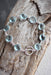 Handmade sterling silver sky blue topaz bracelet by Whitelotus Design featuring faceted gemstones in a modern linked design, showcased on a rustic wooden background.