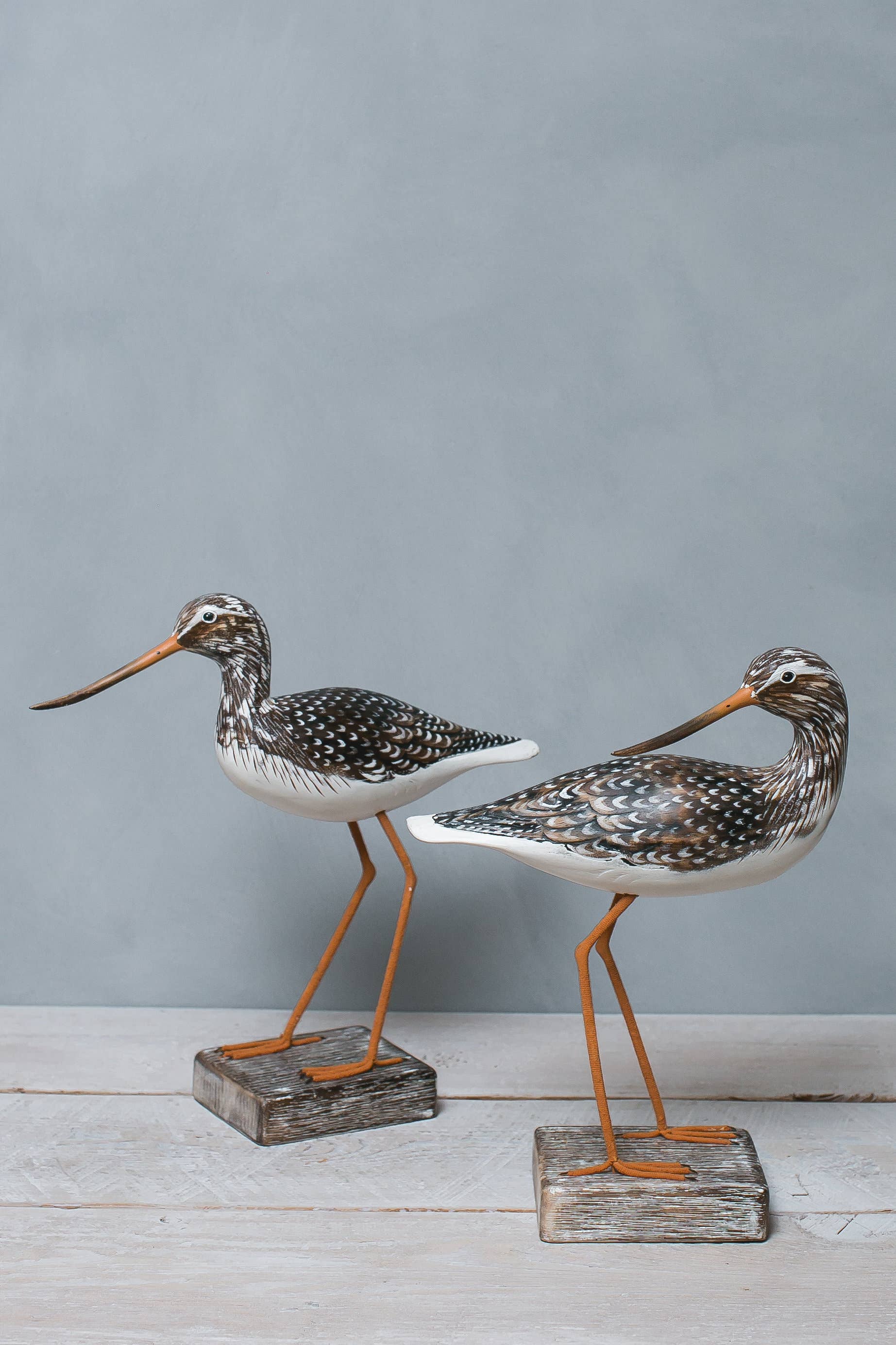 Two elegantly crafted wooden Mini Yellow Legs ornaments by Aviologie, displayed on wooden bases with attention to detail in their artwork, highlighting their handmade quality.