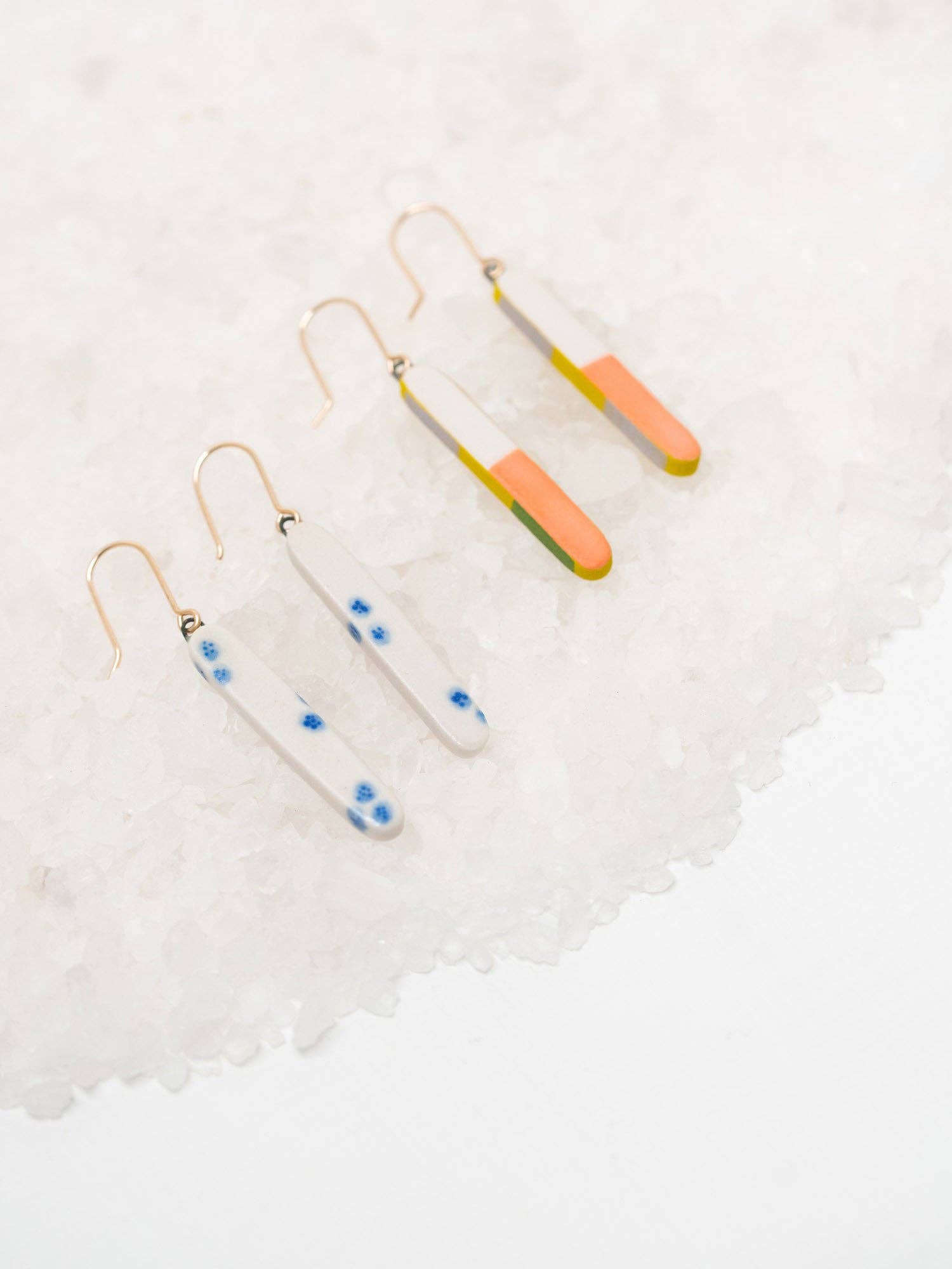 Colorful Skinny Dip Earrings displayed on a bed of white salt, featuring a playful design with vibrant colorways by Twenty Two West.