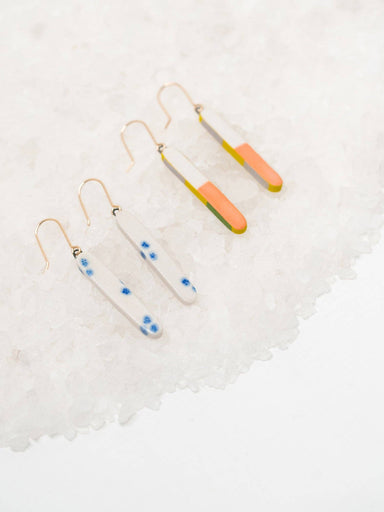 Colorful Skinny Dip Earrings displayed on a bed of white salt, featuring a playful design with vibrant colorways by Twenty Two West.