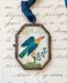 Vintage-style folk bird art locket ornament.