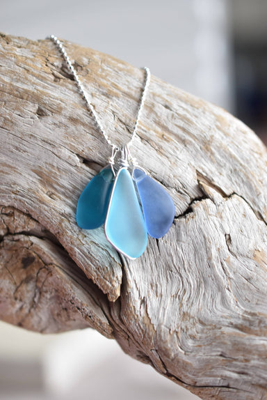 Close-up of the Sterling Silver Recycled Glass Necklace from Whitelotus Design, showcasing three softly frosted blue glass drops, highlighting the craftsmanship and eco-friendly materials.